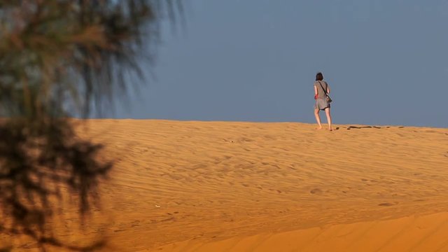 Girl Walks on White Sand Dune Crest on Skyline