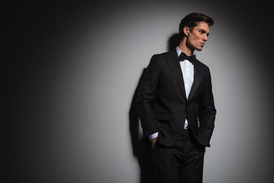 pensive elegant man wearing tuxedo looks away to side