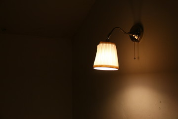 A wall lamp light shines in the dark room