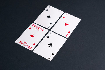 High Angle View of Four Playing Cards Spread Out on Dark Background Showing Aces from Each Suit - Hearts, Clubs, Spades and Diamonds