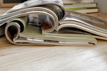 Closeup Stack of colorful magazines on wooden table .