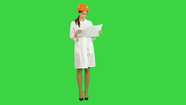 Young engineer woman in safety helmet examining technical drawings on a Green Screen, Chroma Key