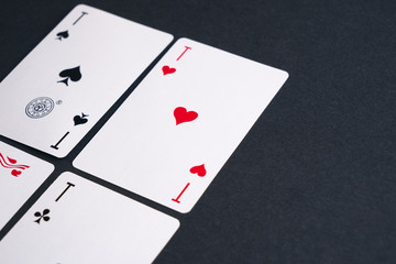 High Angle View of Four Playing Cards Spread Out on Dark Background Showing Aces from Each Suit - Hearts, Clubs, Spades and Diamonds