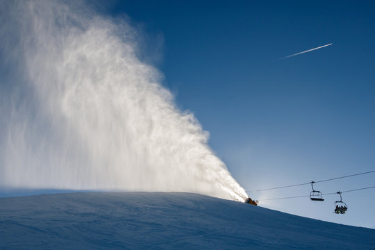 Landscape of snow cannons working at the ski slope on a sunny da