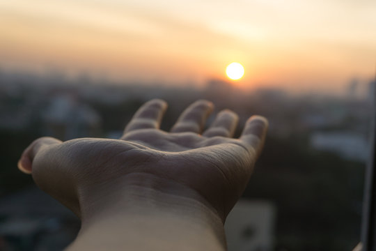 Hand and sunrise over city of  Bangkok Thailand.