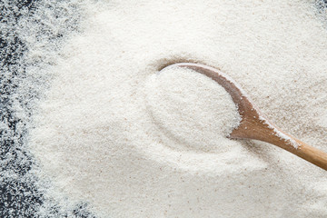 Semolina with wooden spoon on the dark background in the kitchen. Healthy eating and lifestyle.