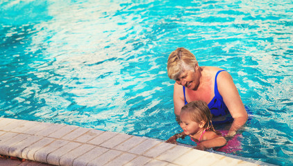 Grandmother teaching granddaughter to swim