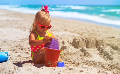 cute little girl play with sand on beach