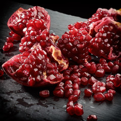 food fresh background of Ripe juicy pomegranate scattered on the black stone
