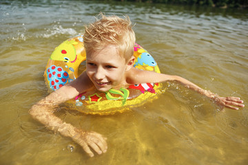 Junge mit Schwimmring badet im See