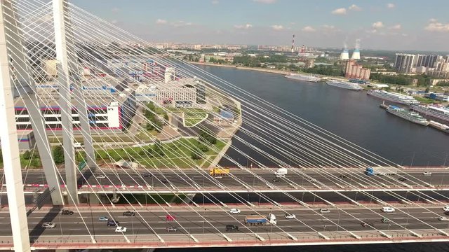 Camera flying along white wire ropes of cable-stayed Bolshoy Obukhovsky Bridge across Neva river. Road traffic is on the KAD highway. St. Petersburg, Russia
