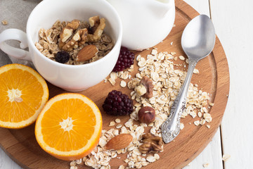 oranges, cereals, nuts and berries on a wooden tray