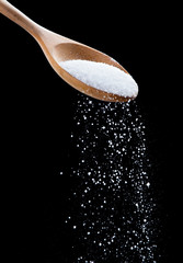 Salt shaker,Sea salt on wooden spoon on black background