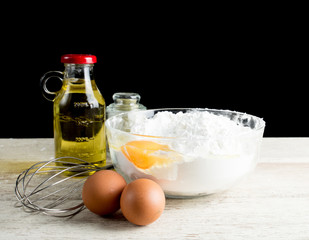 Baking Ingredients (eggs,flour,olive oil) on table wood