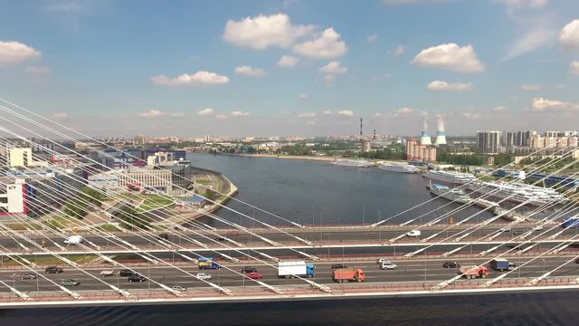 Vehicles drive on the ringroad passing on cable-stayed Bolshoy Obukhovsky Bridge. Aerial view. The bridge across Neva river