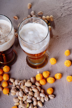 Glasses of beer, cheese balls and pistachio nuts 