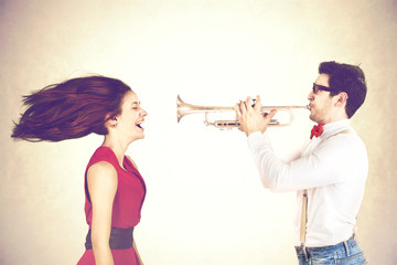 young man plays with power his trumpet messing the hair of his girlfriend