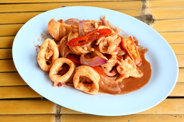 Fried squid with spicy in blue dish against bamboo background
