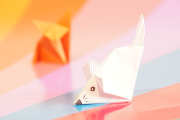 Paper origami fox and mouse are isolated on a colorful background