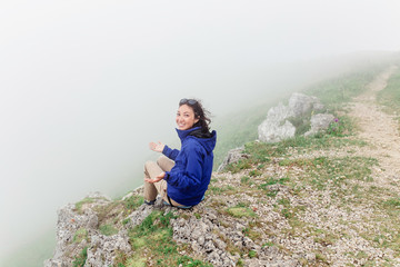 Naklejka premium young happy woman enjoying view of a great foggy landscape on mountain peak