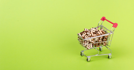 Shopping basket with letters of the alphabet made of wood on a green background