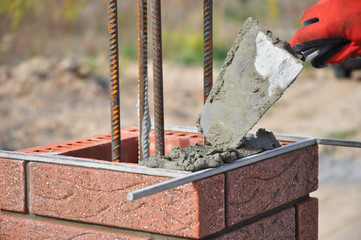 Bricklayer Worker Installing Red Clinker Blocks and Caulking Brick Masonry Joints Exterior Wall...