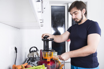 man making the juice from fresh vegetables and fruits in the kitchen