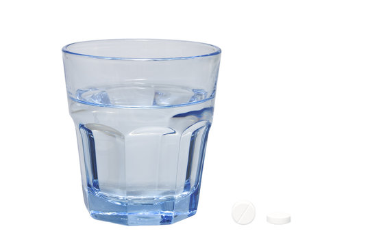 Zwei Tabletten und ein Glas Wasser, freigestellt
