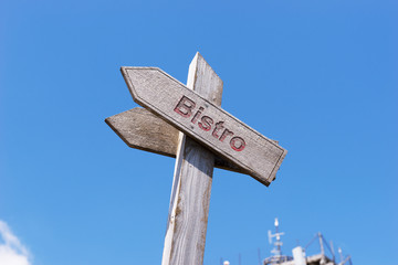 Text Bistro on a wooden sign with blue sky in the background