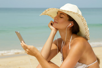 Beautiful woman listening music on the beach