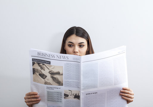 Businesswoman reading newspaper on gray background