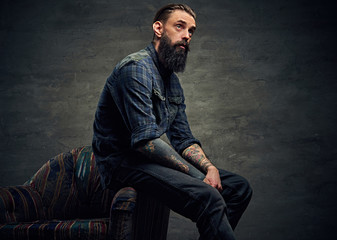 Bearded male sits on a chair.