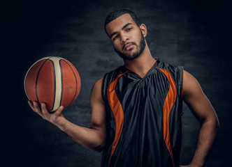 A black man holds a basket ball.