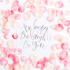 Be bright. Be happy. Be you. Inspirational quote made with calligraphy and floral pattern with pink rose petals. Flat lay, top view