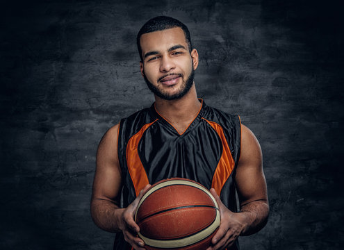 A black man holds a basket ball.