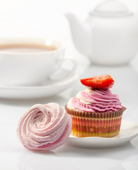 Marshmallows and сupcake on background tea set