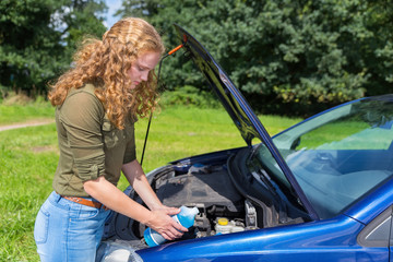 Fototapeta na wymiar Dutch girl filling car reservoir with fluid in bottle