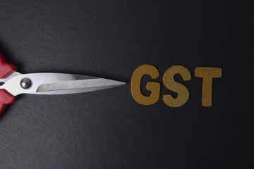Scissors and word of GST on black background