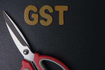 Scissors and word of GST on black background