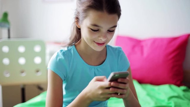 smiling girl texting on smartphone at home