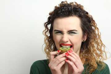 Glamour girl model biting kiwi.