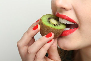 Glamour girl model biting kiwi.