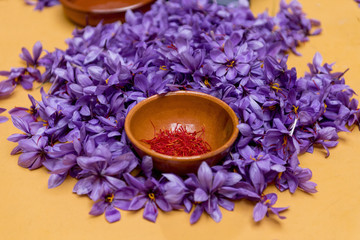 Fototapeta na wymiar Close-up of a bowl with saffron pistils on a pile of roses saffron