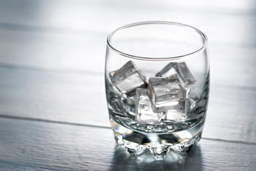 Glass with ice cubes on the wooden table