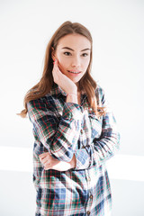 Pensive beautiful young woman standing with hands folded and thinking