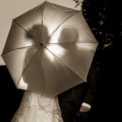 Jeunes mariés derrière une ombrelle à contre jour.