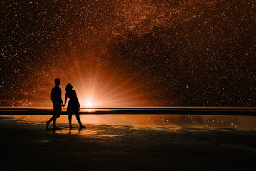 Silhouettes of loving couple, walking along the beach and imagine in the sky, the universe, stars and planets. People are on another planet. Elements of this Image Furnished by NASA   - obrazy, fototapety, plakaty