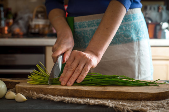 Cutting spring onion on the wooden board horizontal