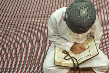 Boy reading al Quran during fasting month (Ramadhan ). DOF and copy space.