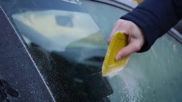 Autoscheibe der T&uuml;r mit dem Eiskratzer vom Eis befreien